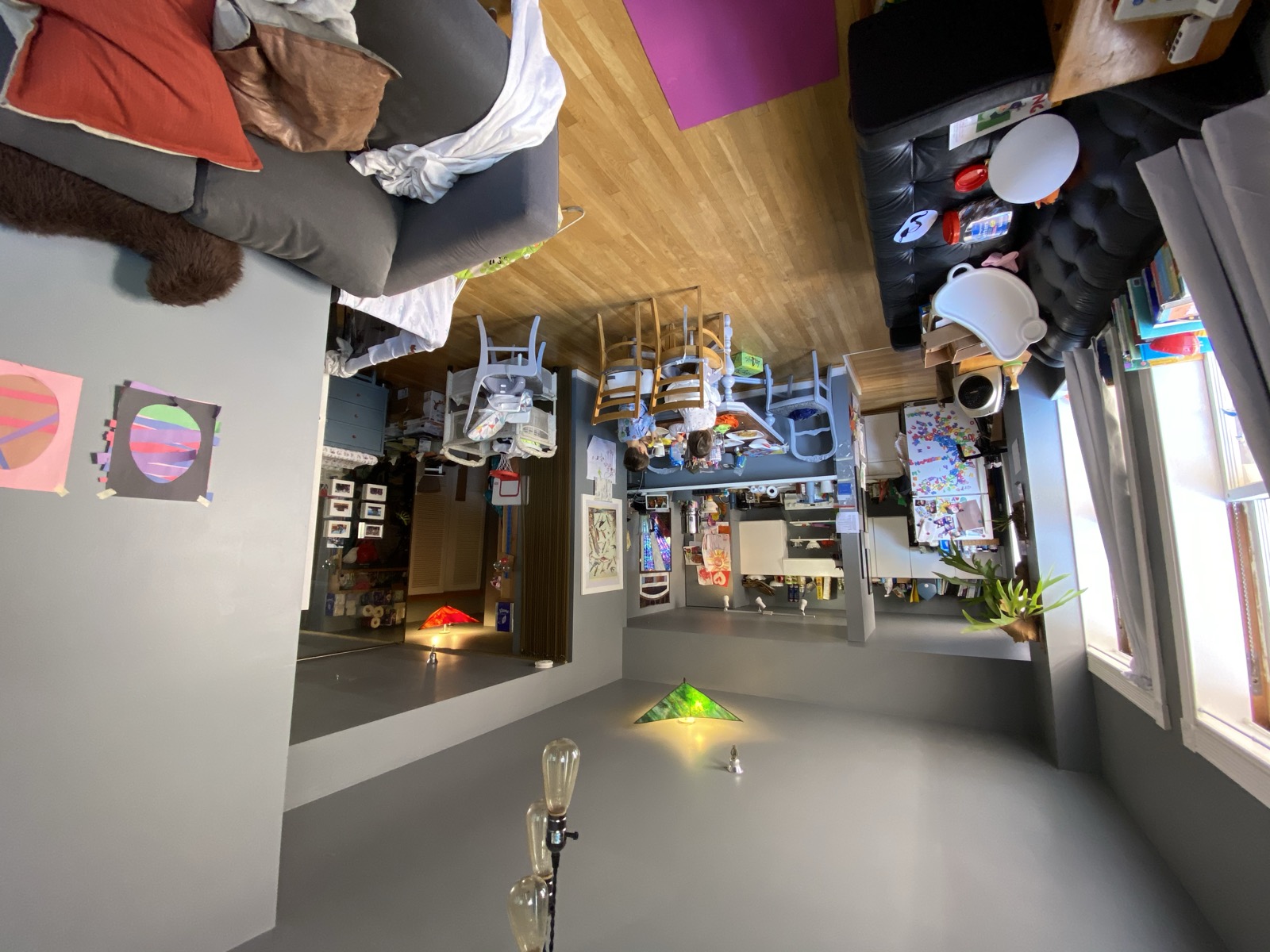 Children at the dining table in a compact apartment filled with toys, books, and family artwork