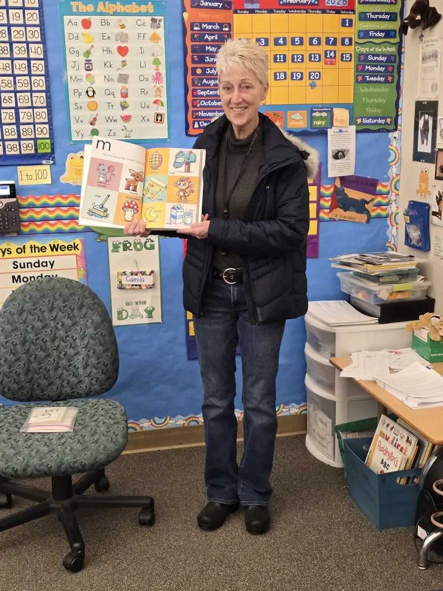 Educator holding open the Alphabet Sounds book to the m sound page in a classroom